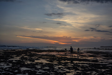 people on beach at sunset with iconic red sky