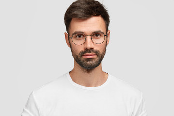 Headshot of handsome male freelancer with appealing look, has dark beard and mustache, looks...