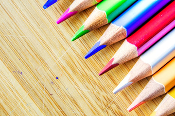 Obraz premium multicolored pencils on wooden background forming a pattern with copy space