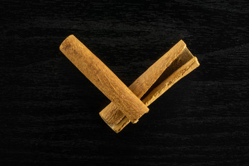 Group of two whole dry brown cinnamon stick flatlay on black wood