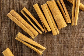 Lot of whole dry brown cinnamon stick flatlay on brown wood
