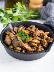 Turkey meat stew with champignon mushrooms and spices served in cast iron skillet on white wooden board