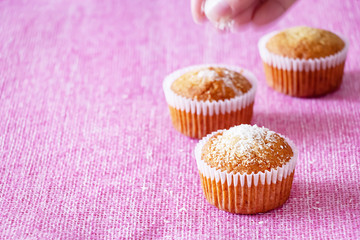 Homemade vanilla muffins with coconut powder. Pink background. Copy space. Selective focus. Blur motion.