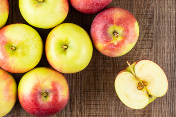 Lot of whole one slice of fresh red apple james grieve variety flatlay on brown wood