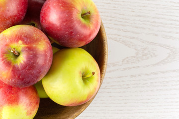 Lot of whole fresh red apple james grieve variety with wooden bowl flatlay on grey wood