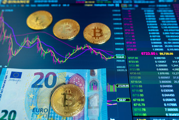Paper bill Euro twenty EUR, blurred background. The electronic schedule of bitcoin on the exchange, volume trades, on the monitor lie gold coins bitcoin.