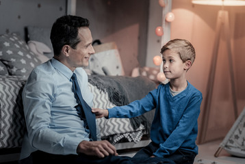 Obraz premium Need your advice. Cheerful boy sitting near his daddy while having friendly talk