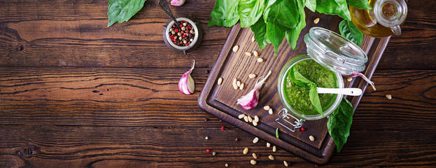 Homemade pesto sauce fresh basil, pine nuts and garlic on wooden background. Italian food. Top view. Flat lay. Banner