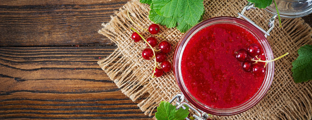 Red currant jam in a jar on a wooden background. Tasty food. Flat lay. Top view. Banner