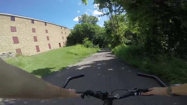 Point of view slow motion shot of boy coasting down a hill down a nature bike path.