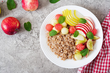 Healthy breakfast. Buckwheat or porridge with fresh melon, watermelon, apple and pear. Tasty food. Top view, copy space, flat lay