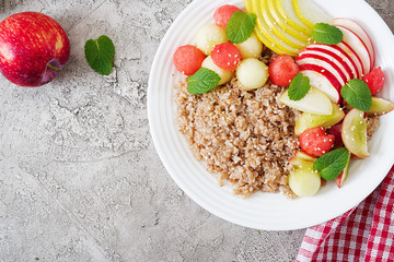 Healthy breakfast. Buckwheat or porridge with fresh melon, watermelon, apple and pear. Tasty food. Top view, copy space, flat lay
