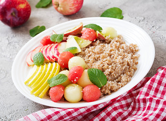 Healthy breakfast. Buckwheat or porridge with fresh melon, watermelon, apple and pear. Tasty food.