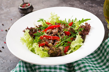 Healthy salad bowl with  beef meat, sweet peppers, onions and mixed greens, lettuce, arugula on dark background. Food and health.