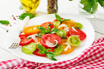 Colored tomato salad with onion and basil pesto. Vegan food.