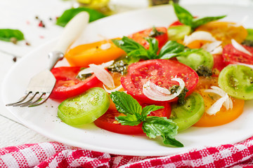 Colored tomato salad with onion and basil pesto. Vegan food.