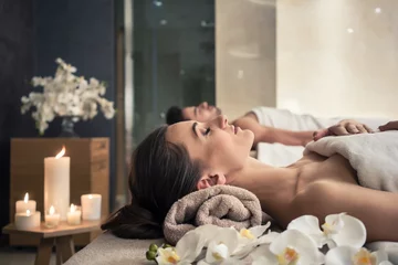 Fototapeten Junger Mann und Frau liegen auf Massagebetten im asiatischen Luxus-Spa und Wellnesscenter © Kzenon