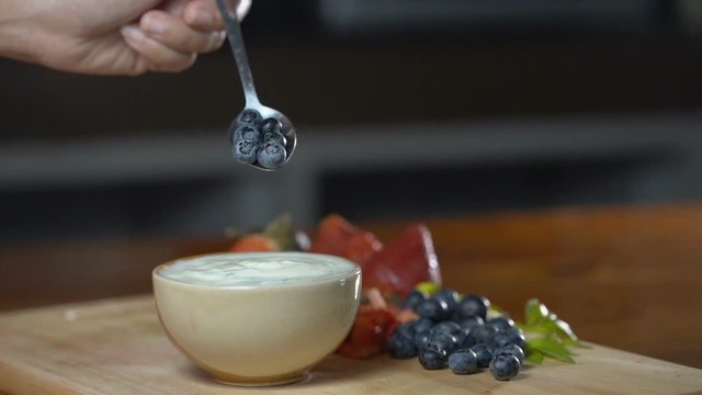 Close up, Take a scoop of yogurt in a cup with strawberries and blueberries in a spoon.