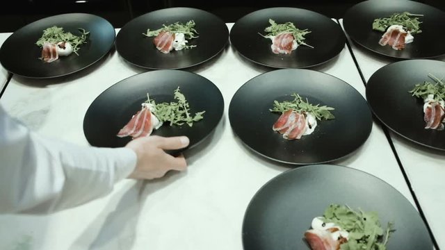 Chef preparing and decorating food, many round plates&nbsp;with meal in kitchen in restaurant
