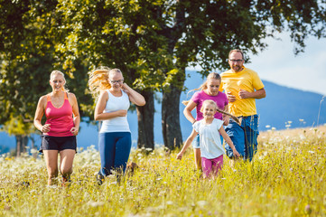 Obraz premium Family, mother, father and kids running for sport over a meadow