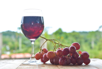 red grapes and a glass of wine on wooden table. selective focus.