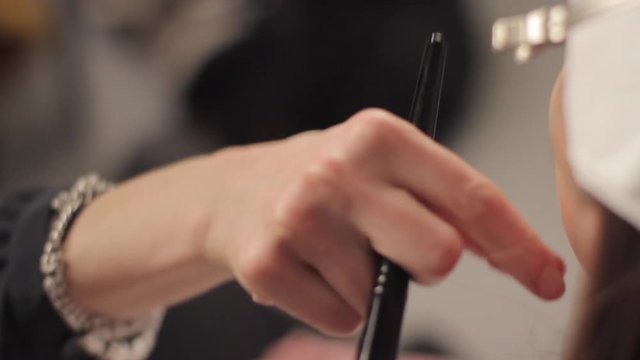 Close-Up of Professional Makeup Artist's Hand with Brush doing Make up on a Model