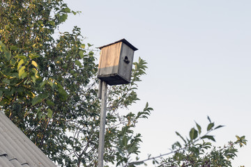 Wooden birdhouse on the background of the sky, wood and roof