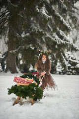 Fairy tale girl. Portrait a little girl in a deer dress with a painted face in the winter forest. Big brown antler