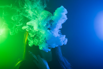 Young woman smoking vape or e-cigarette in neon light