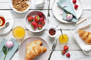 Breakfast food table. Brunch set, meal variety with fried egg, croissants, granola and fresh strawberry. Overhead view
