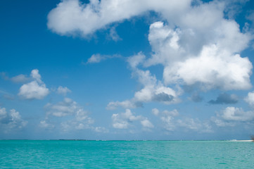 Fototapeta na wymiar Ocean background, bright colors of turquoise water and blue sky with some clouds