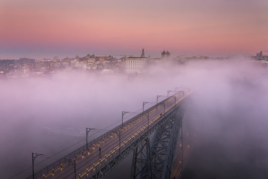 Famous bridge Ponte dom Luis covered with morning fog during sunrise in Porto, Portugal