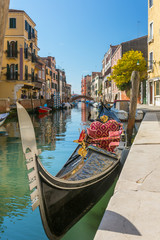 Parked gondola waiting for tourists at side canal in Venice, Italy