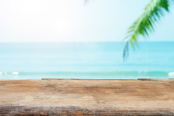 Old wood table top on bOld wood table top on blurred beach background with coconut leaf. Concept Summer. Selective focus,lurred beach background with coconut leaf. Concept Summer