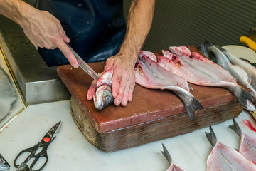 a man eviscerating  fresh fish