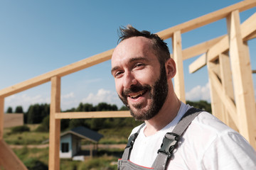 The man is a builder on the roof of a wooden frame house.