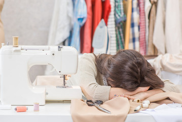 Tired seamstress lying near sewing machine. Hobby sewing as a small business concept