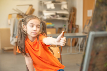 Little girl measuring proportions with his brush for drawing