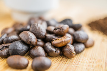 macro of coffee beans with cup on wooden board