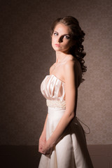Brown-haired woman in white wedding dress with hair and make-up in vintage interiors.