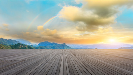 Wood square floor and mountains with rainbow at sunset