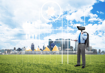 Camera headed man standing on green grass against modern cityscape