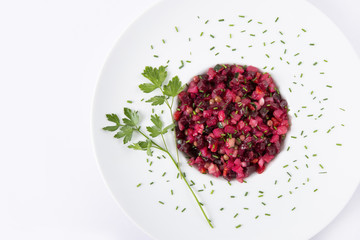 Salad with beets. Vinegret is a traditional Russian salad made from beets and vegetables in a white plate. The background is white. Top view. Copy space. Horizontal shot.