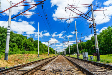 Fototapeta na wymiar View on a railroad track and white clouds in blue sky