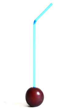 Ripe plum with a stuck blue cocktail straw in pulp. Isolated. White background