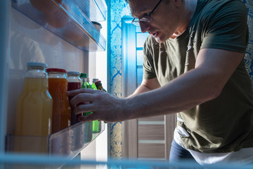 View from inside a fridge of a man taking a juice