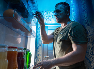 Man looking in a fridge for something to snack on