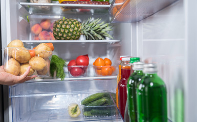 Hand taking container with potatoes from fridge © kolotype