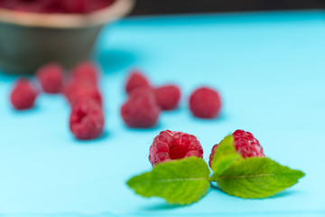 Fresh raspberries with mint leaf on blue table