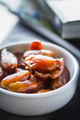 Date fruits on white plate whith book